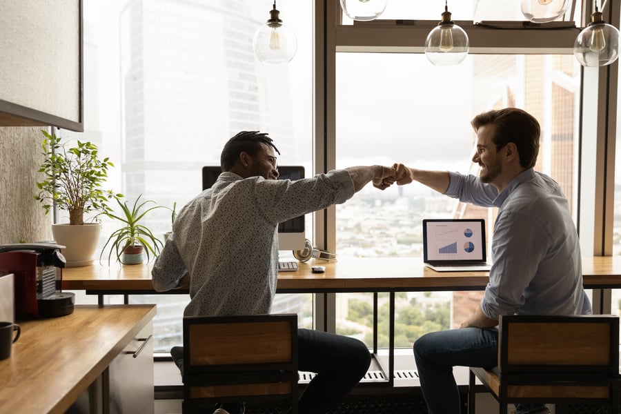 Two businessmen fist-bumping in an office