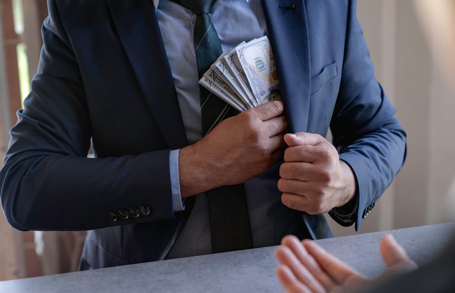 A man in a suit pocketing cash