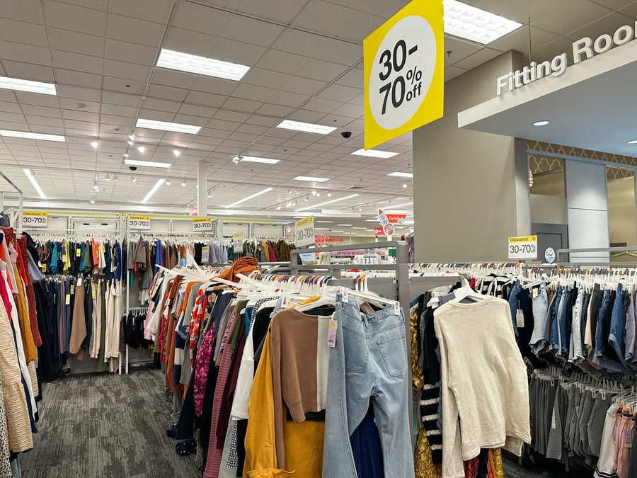 An overstocked retail store with lots of clothing being advertised at big discounts