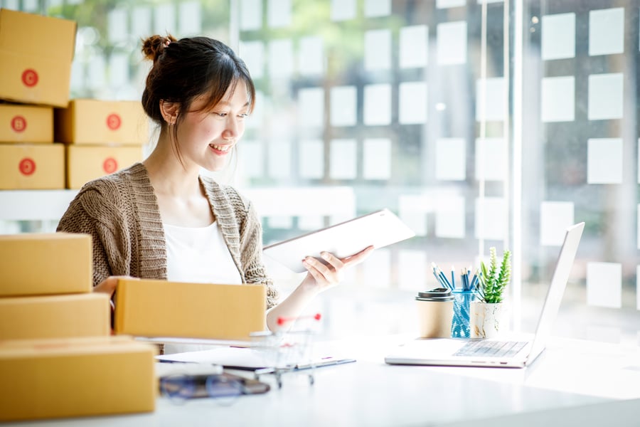 A woman smiles at a contract surrounded by boxes